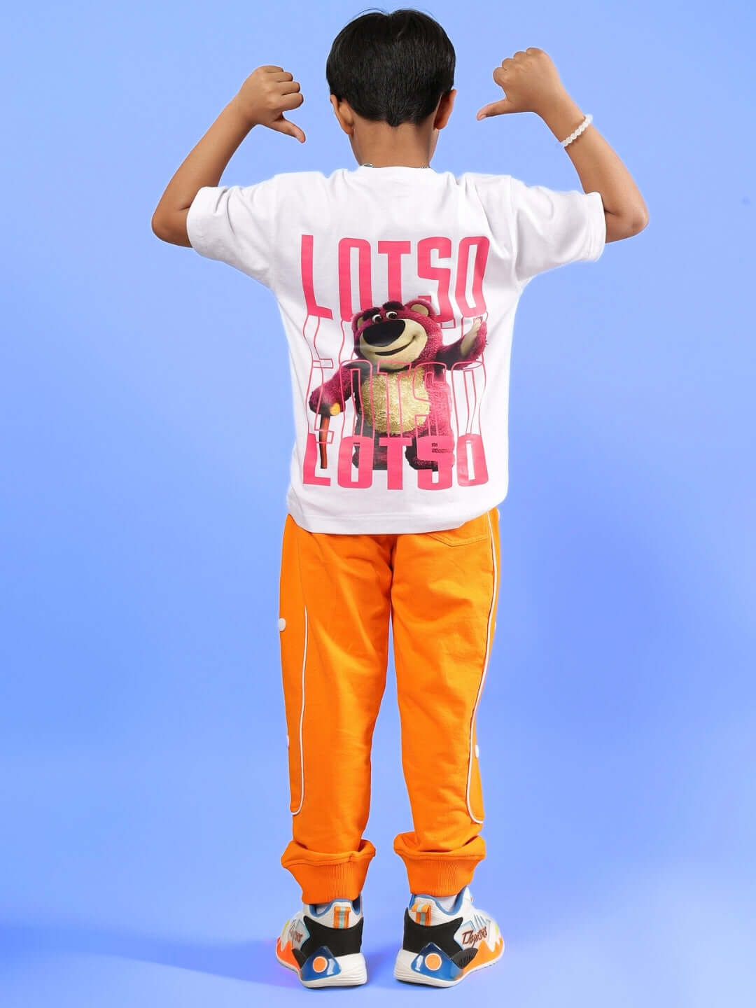 Child wearing white "LOTSO" graphic T-shirt with orange pants, posing playfully against blue background. Unisex co-ord for boys and girls.
