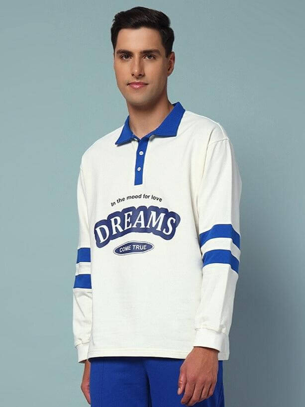 Man wearing LOVE DREAMS oversized off-white sweatshirt with royal blue accents, made from cotton French Terry Lycra, against a plain background.