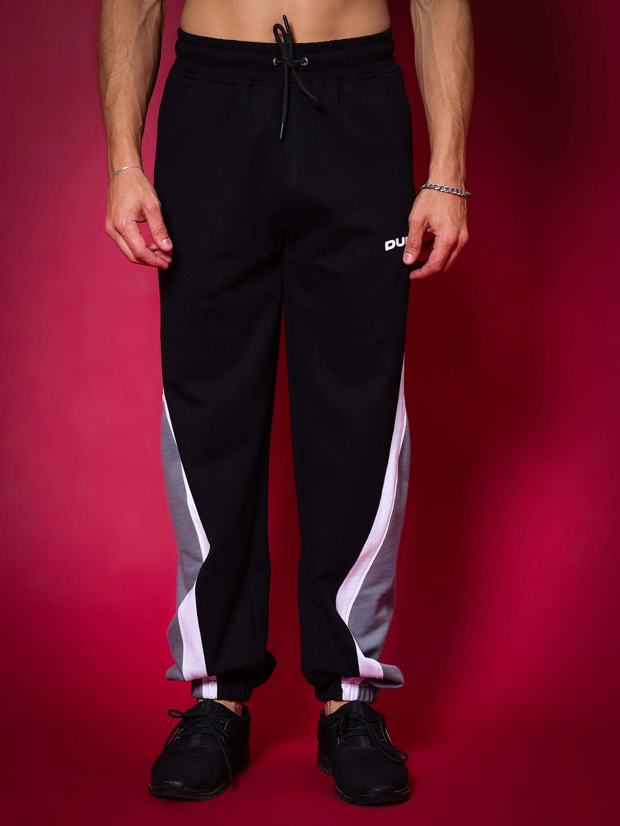 Model wearing black-grey Love Triangle Baggy Joggers by DUDS, showcasing sporty style with white stripe detailing.
