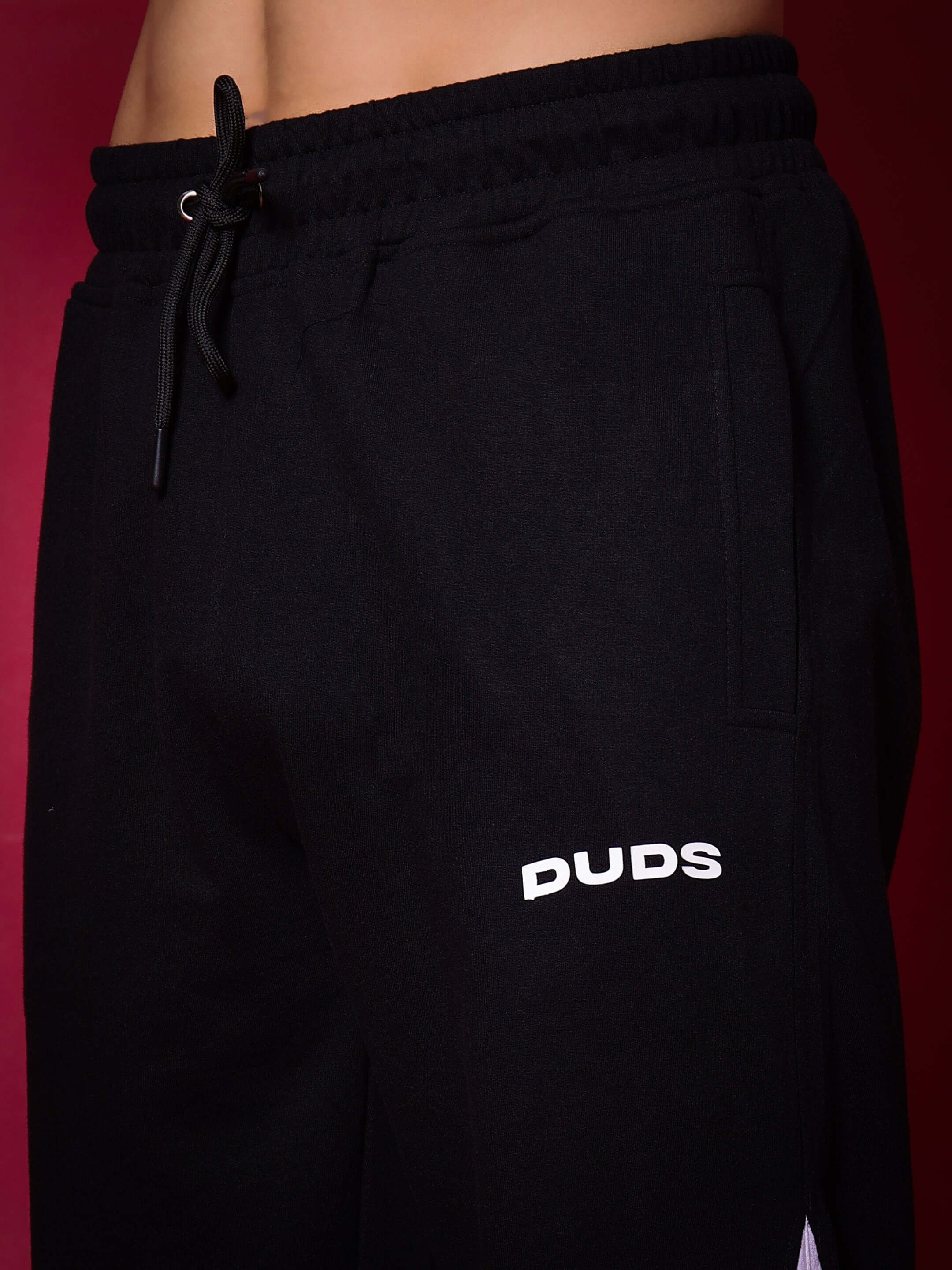 Close-up of black-grey LOVE TRIANGLE baggy joggers by DUDS, featuring adjustable drawstring waist, designed for custom fit and comfort.