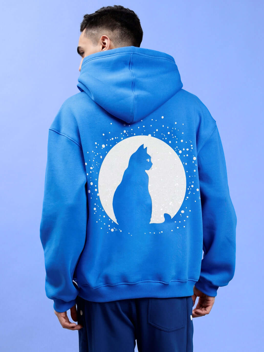 Back view of man wearing LUNA FLECCE OVERSIZED HOODIE ROYAL BLUE with cat and moon design.