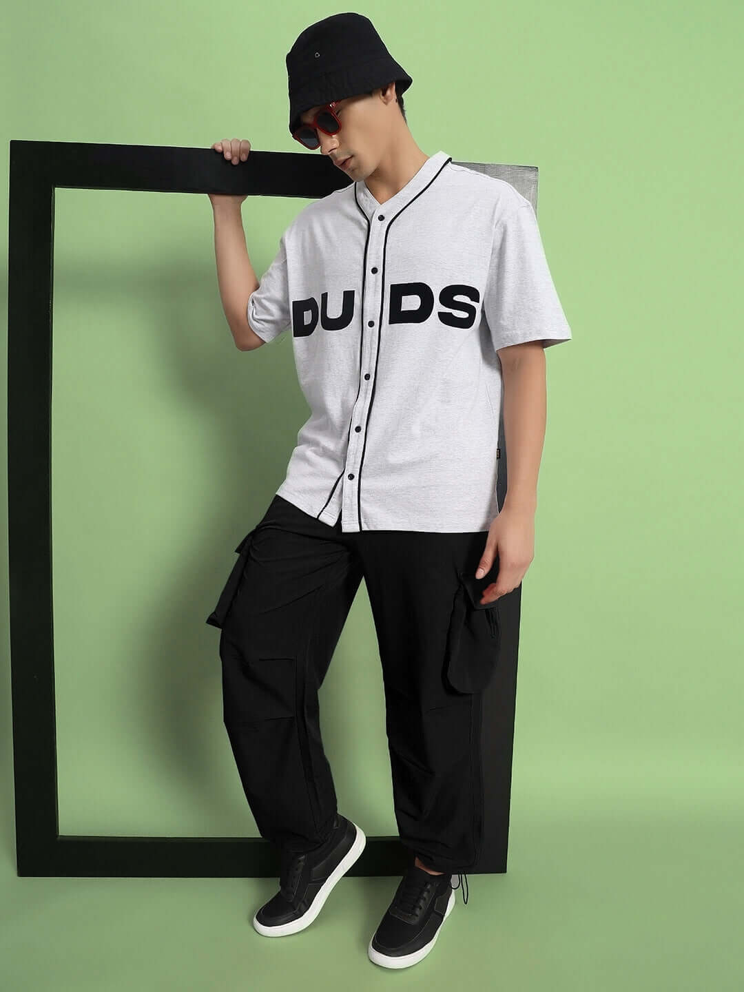Model wearing black Mabel relaxed fit cargo pants with a white DUDS shirt, accessorized with a black bucket hat and sunglasses.