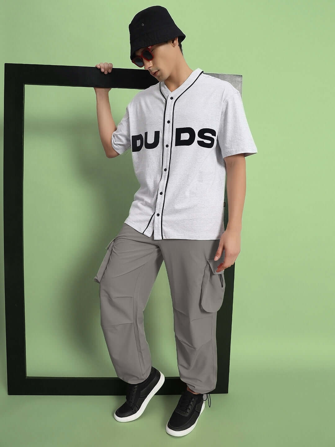 Model wearing MABEL relaxed fit grey cargo pants with a casual DUDS shirt and bucket hat, perfect for urban style enthusiasts.