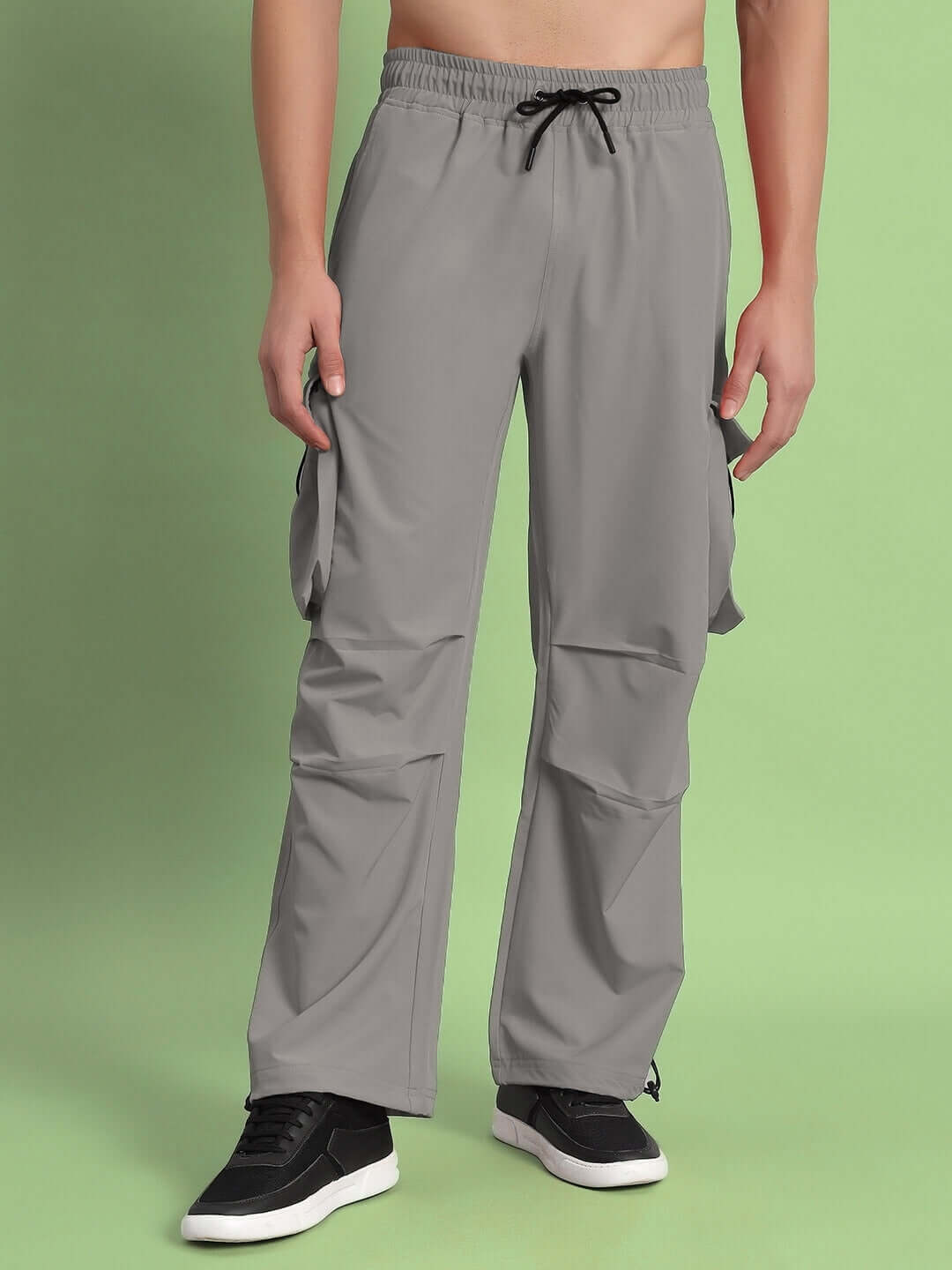 Grey relaxed fit cargo pants with drawstring waist, showcased on a green background. Available in custom sizes for prepaid orders.