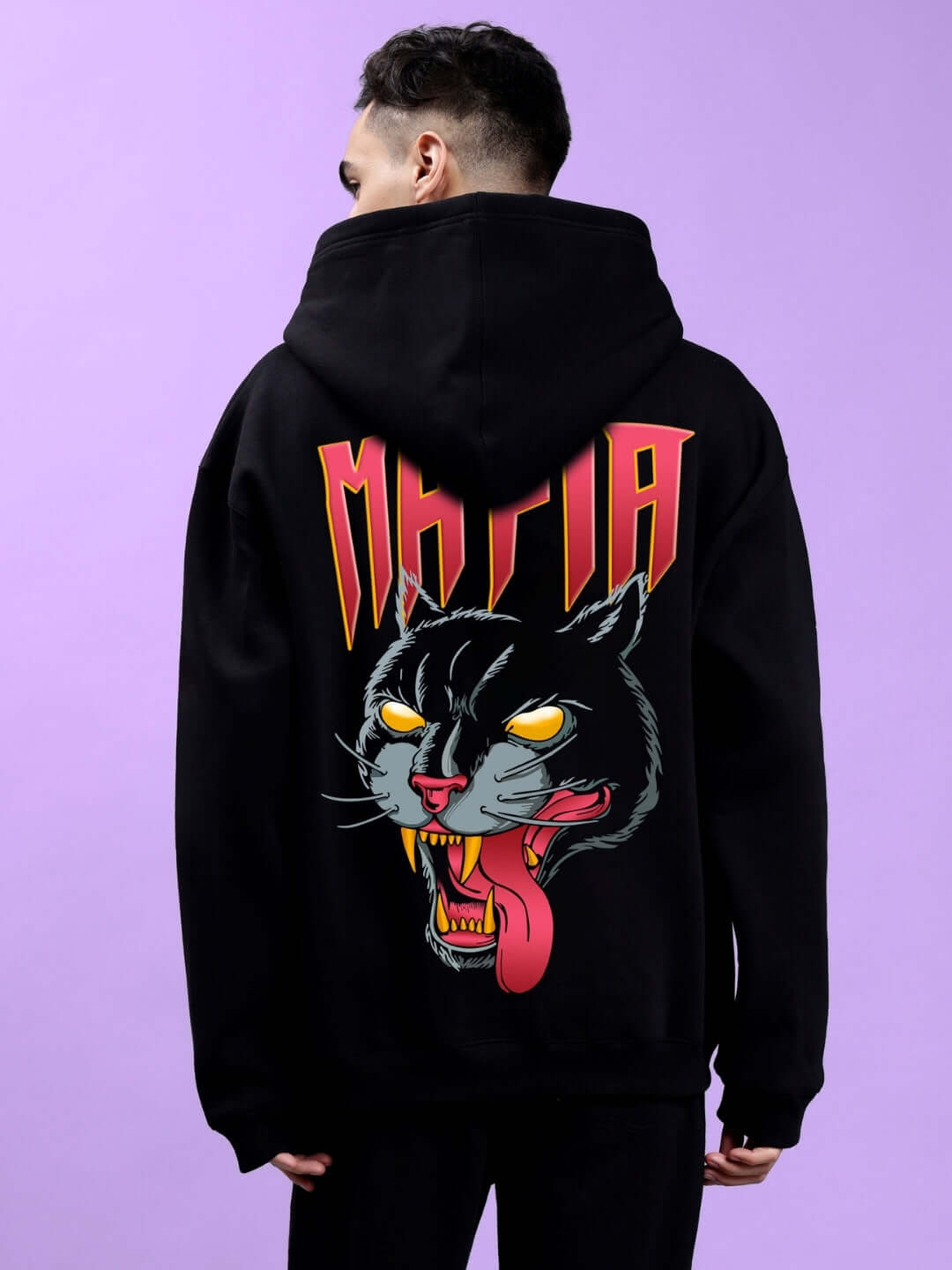 Back view of MAFIA FLEECE OVERSIZE HOODIE BLACK with bold graphic design on a model against a purple background.