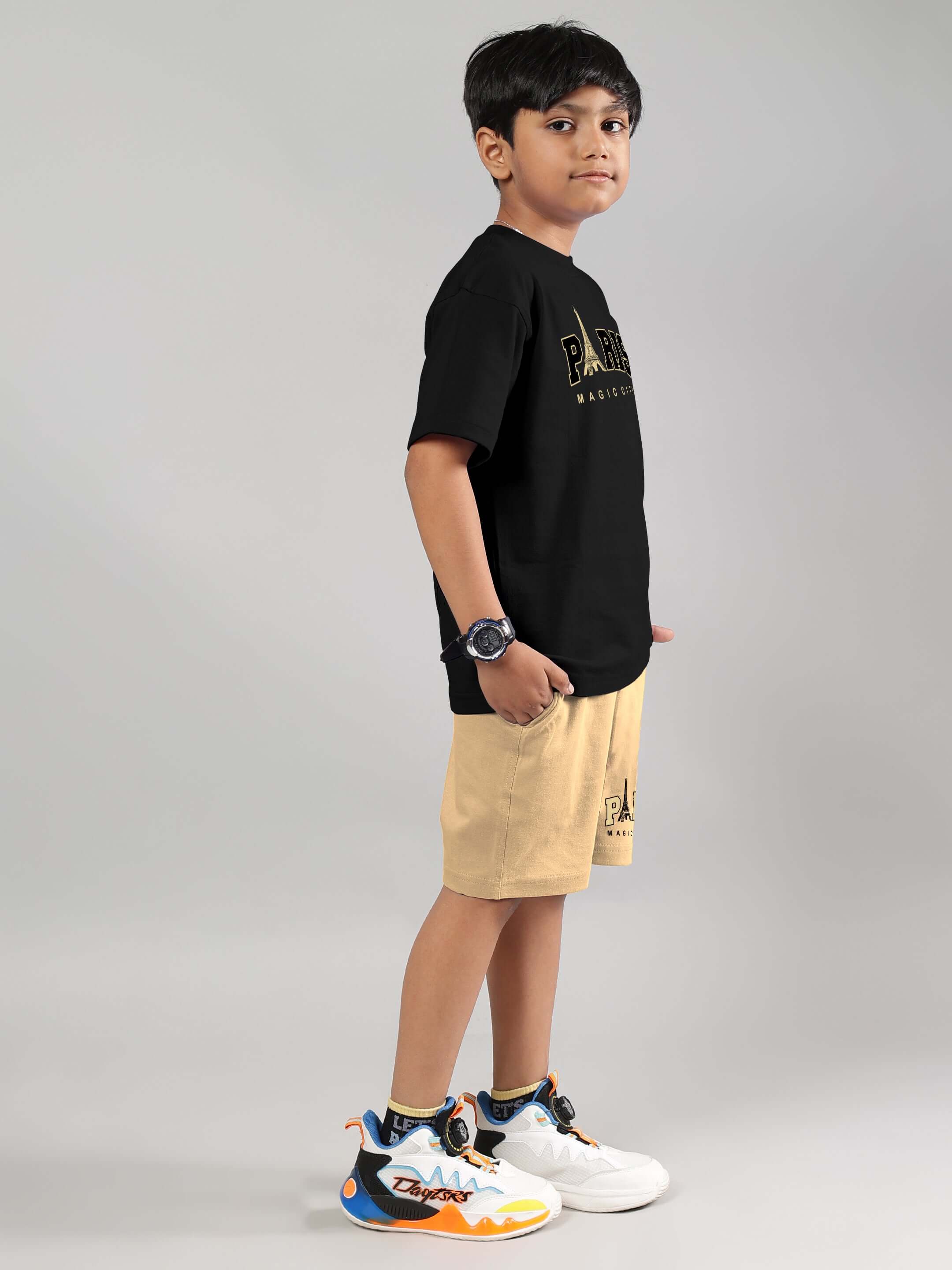 Boy wearing Magic City co-ord set in black and beige, featuring a black T-shirt and beige shorts, styled with trendy sneakers.