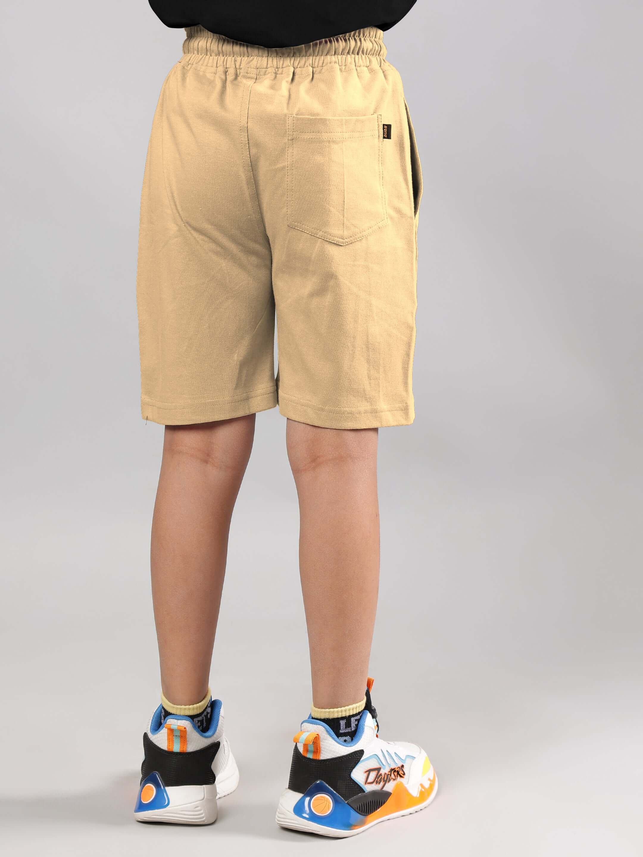 Beige Magic City shorts for boys and girls, made to order by DUDS, shown from the back, worn with colorful sneakers.