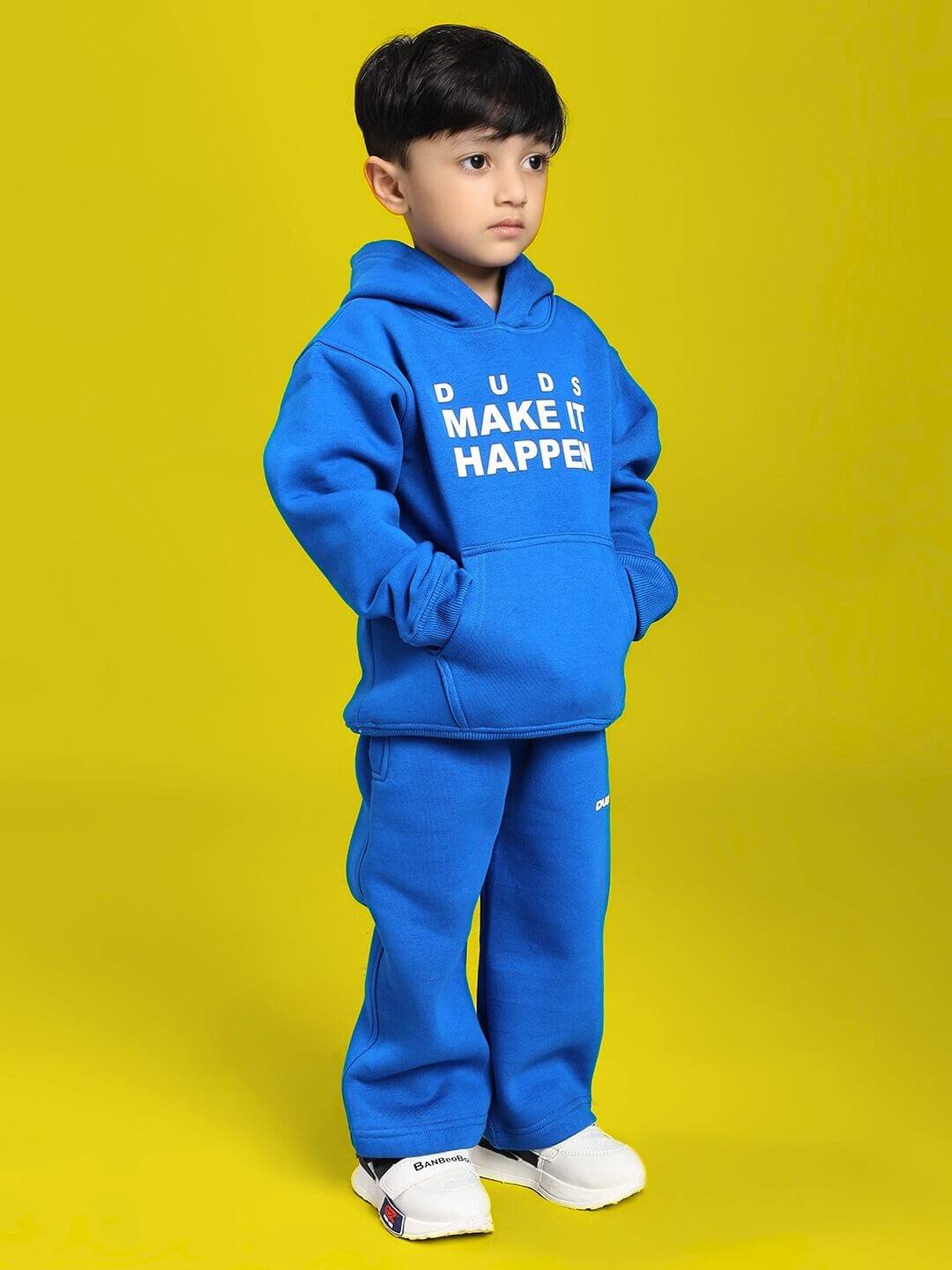 Child wearing MAKE IT HAPPEN FLEECE CO-ORD FOR BOYS AND GIRLS ROYAL BLUE standing against yellow background.