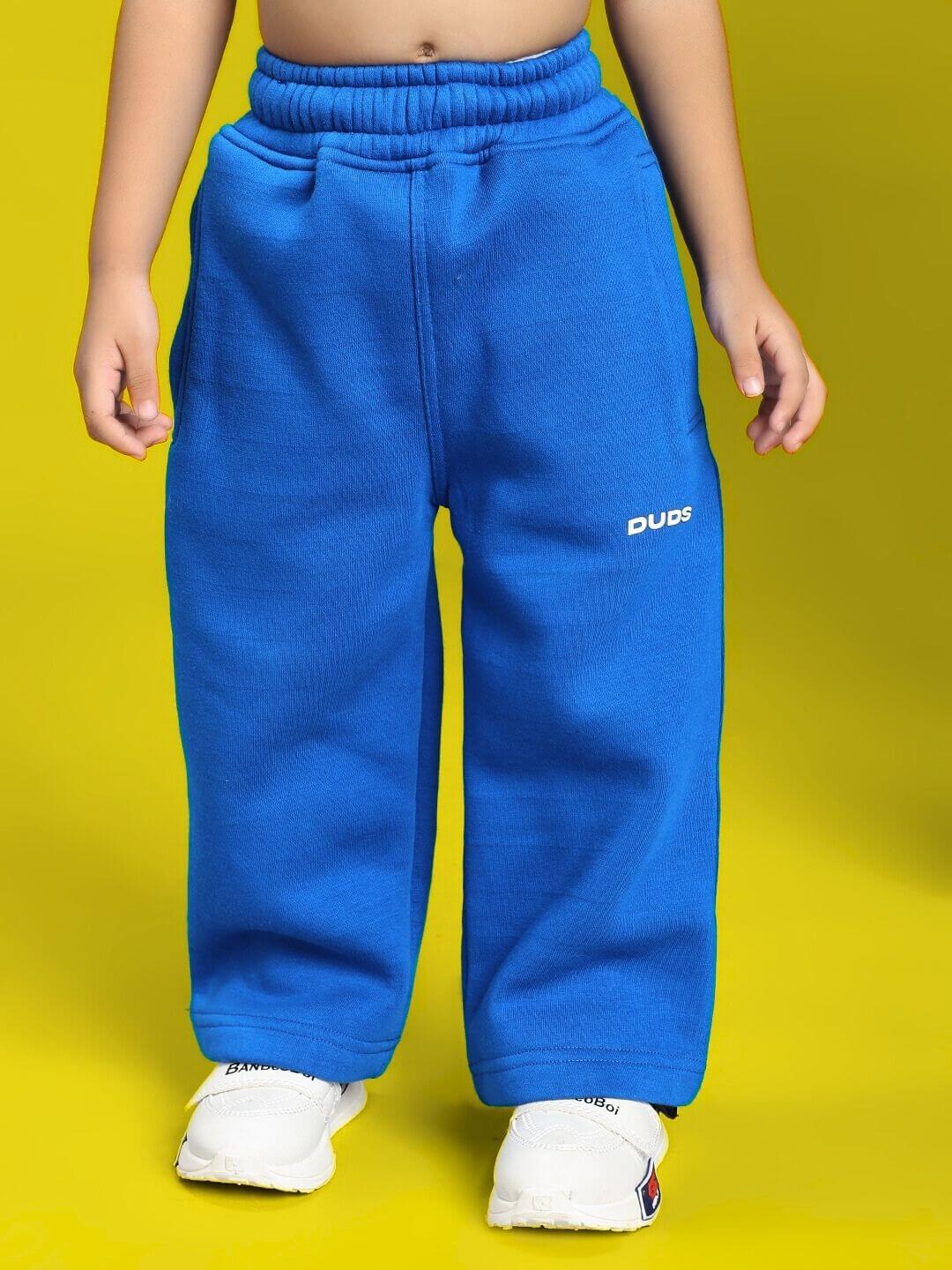 Child wearing MAKE IT HAPPEN FLEECE CO-ORD FOR BOYS AND GIRLS ROYAL BLUE pants standing on yellow background.