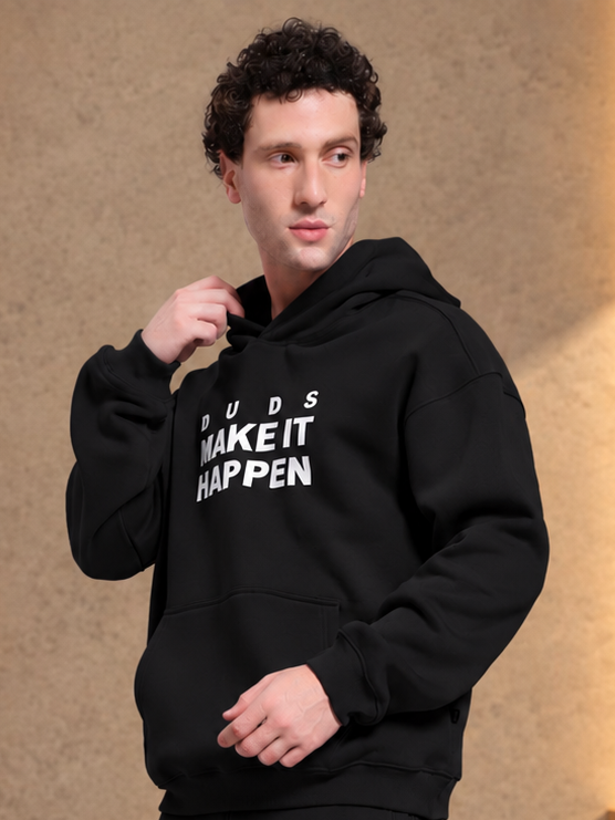 Man wearing MAKE IT HAPPEN FLEECE HOODIE BLACK with bold printed graphic design