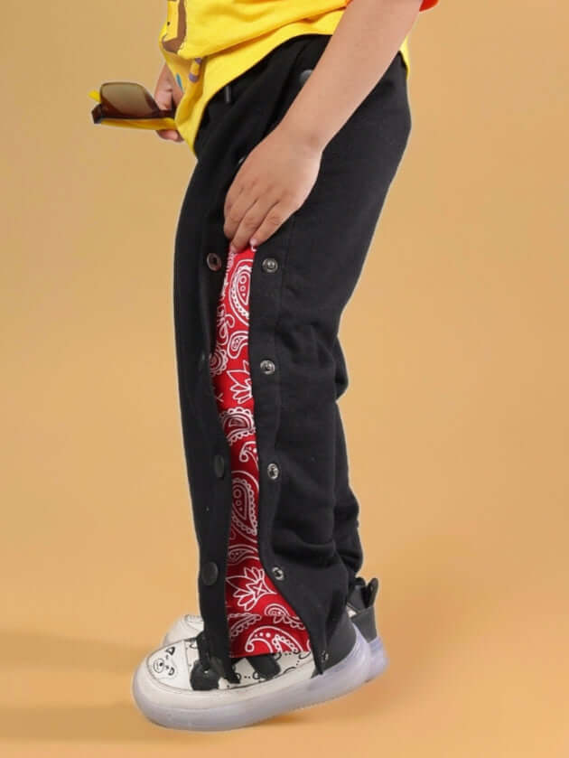 Child wearing Mambo Jogger for Boys & Girls, black with red side panels, paired with sneakers, perfect for casual wear.