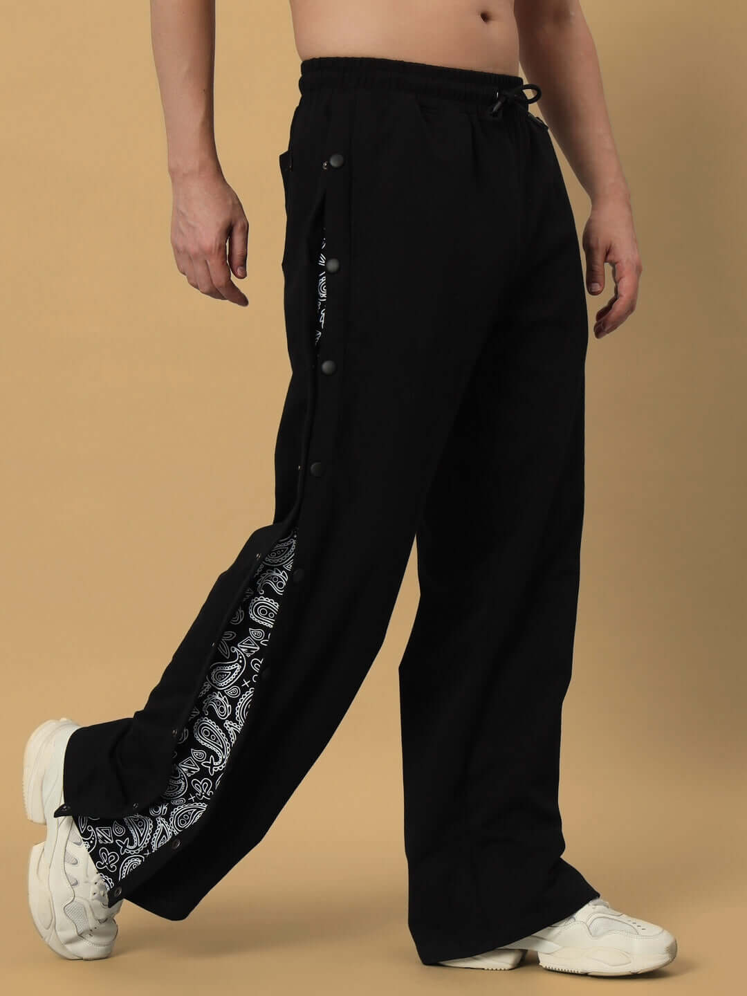 Model wearing MAMBO Joggers in black with side buttons and paisley detail, showcasing relaxed fit and customization options by DUDS.