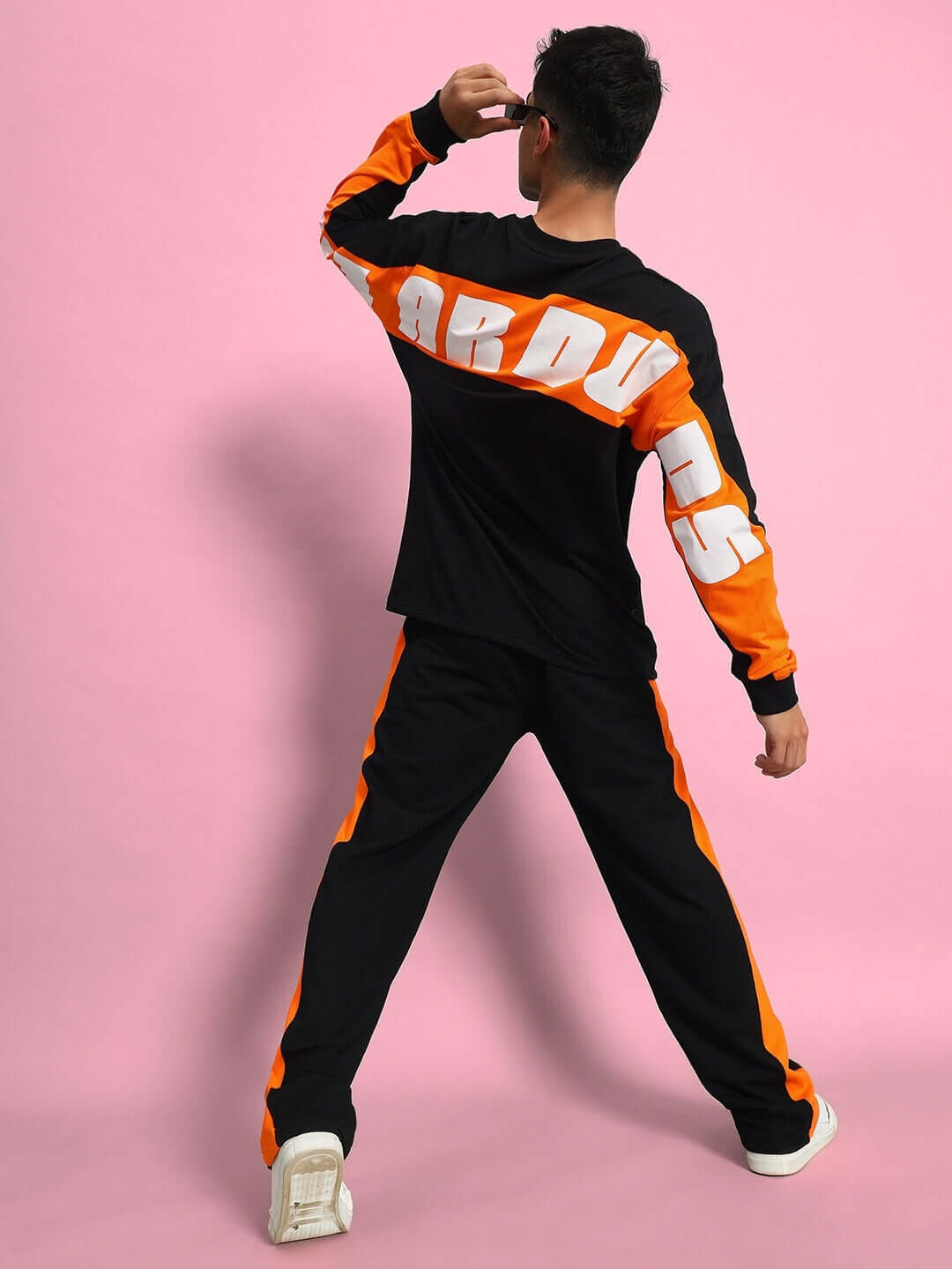 Model wearing black oversized co-ord set with orange detailing, featuring relaxed fit joggers and a bold graphic print on the sleeves.