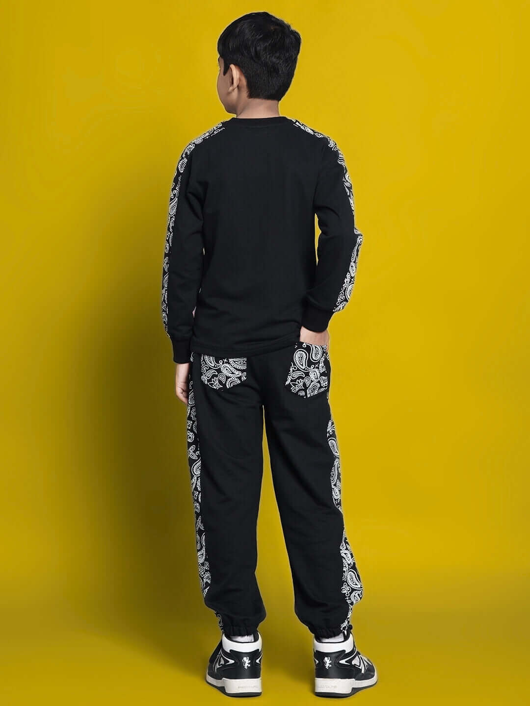Child wearing Masha Co-ord set for boys and girls in black, featuring intricate patterns, styled by DUDS against a vibrant yellow backdrop.