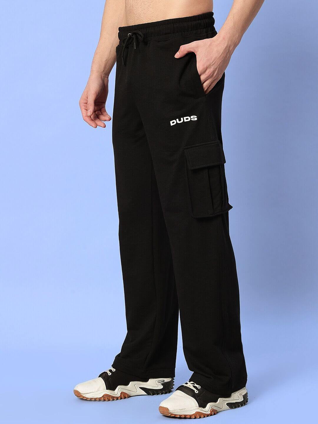 Man wearing black cargo pants with "Duds" logo, featuring side pockets. Casual fashion suitable for everyday wear.