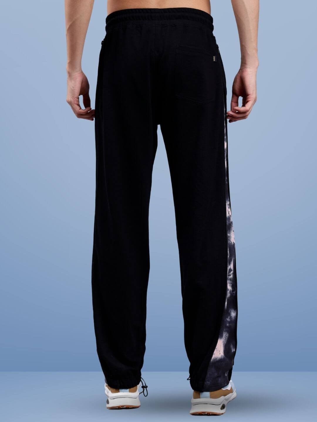 Back view of men's black joggers with panel design, worn with casual sneakers.