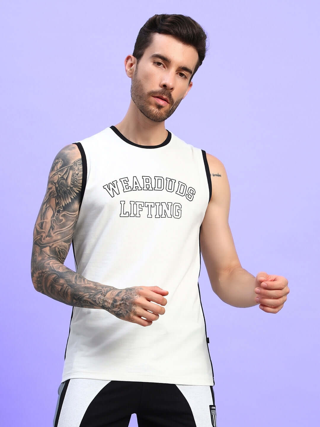Model wearing Lift Up Regular Fit T-Shirt Off White with streetwear style and tattooed arm, standing against purple background.