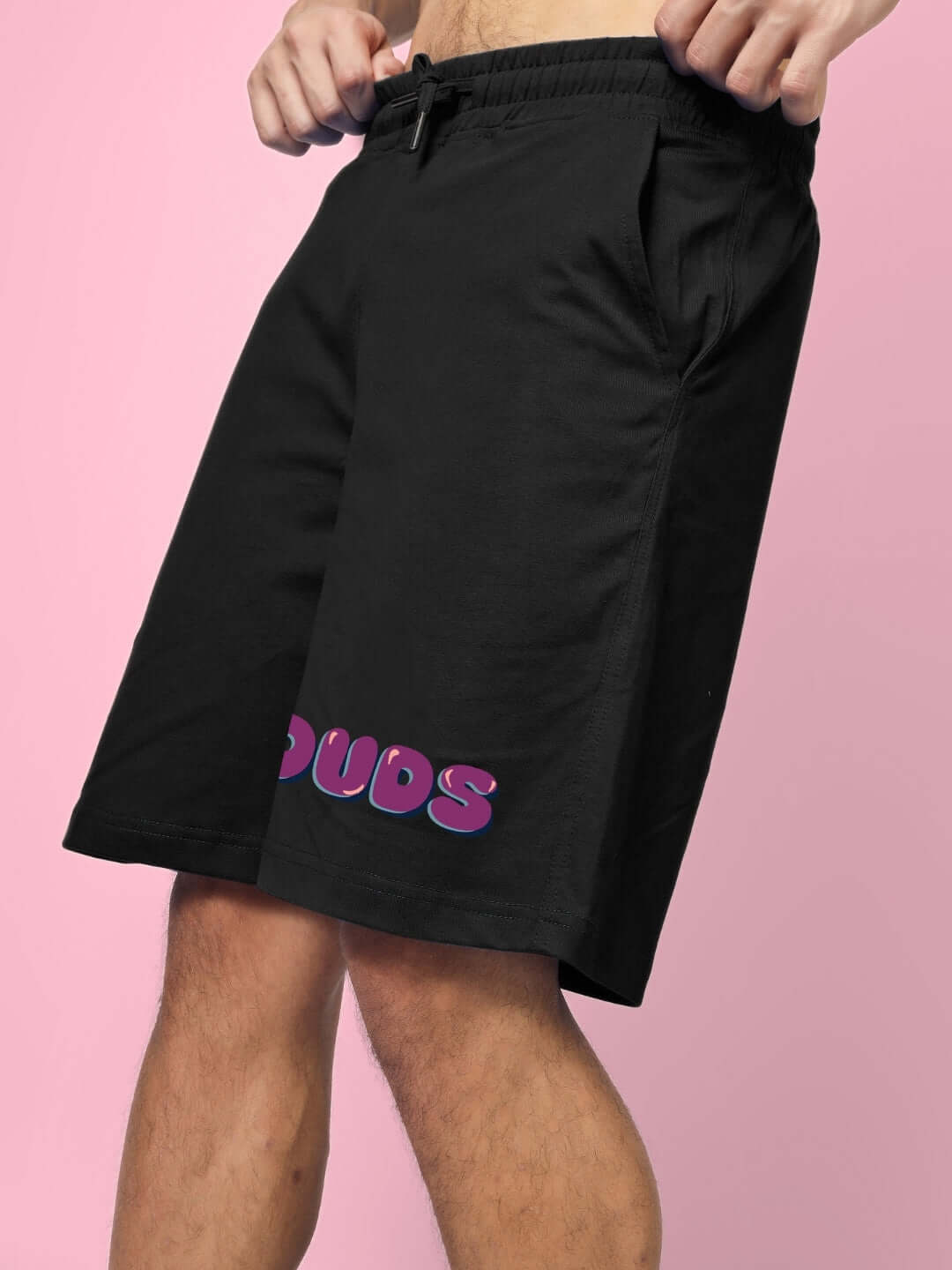 Black shorts with purple logo, modeled on a pink background, part of the NO POS WOW SUMMER CO-ORD SET WHITE BLACK collection.