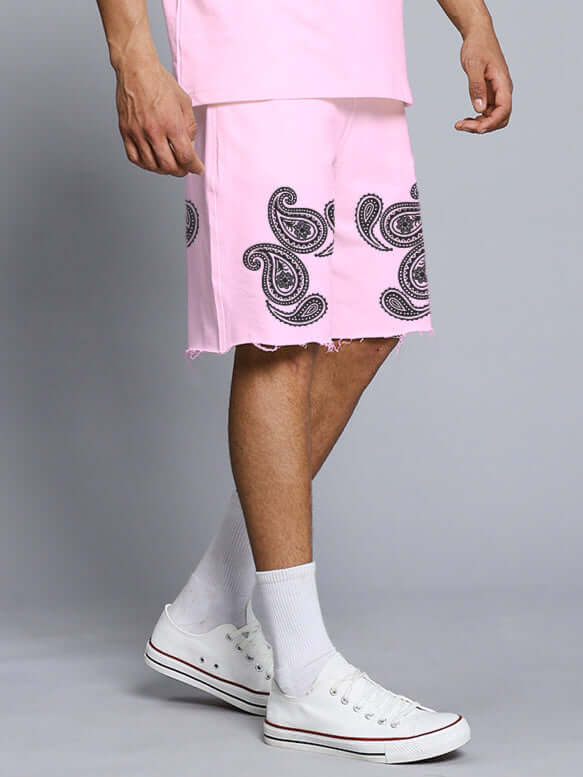 Man wearing Messi Paisley Print Regular Fit Shorts Pink with paisley design and white sneakers