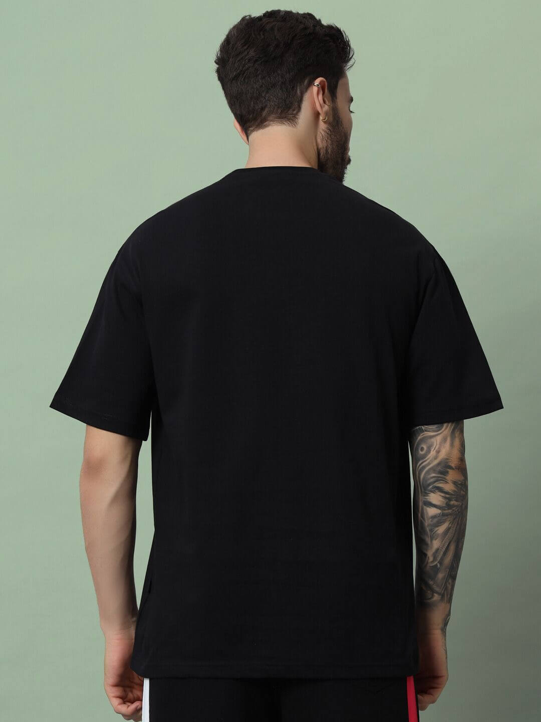 Back view of a black Metallica over-sized t-shirt being worn, showcasing the fit and style against a neutral background.