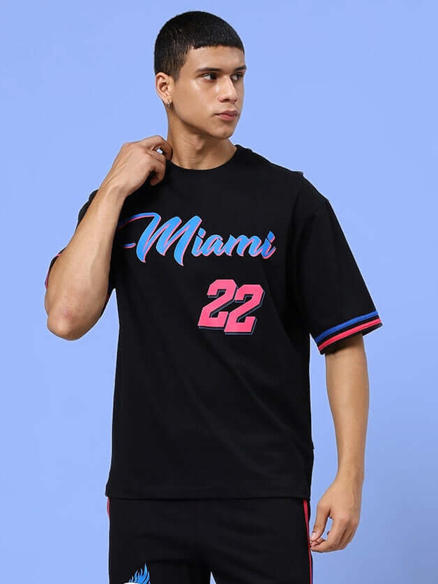 Man wearing MIAMI OVER-SIZED T-SHIRT BLACK with Miami text, casual streetwear style.
