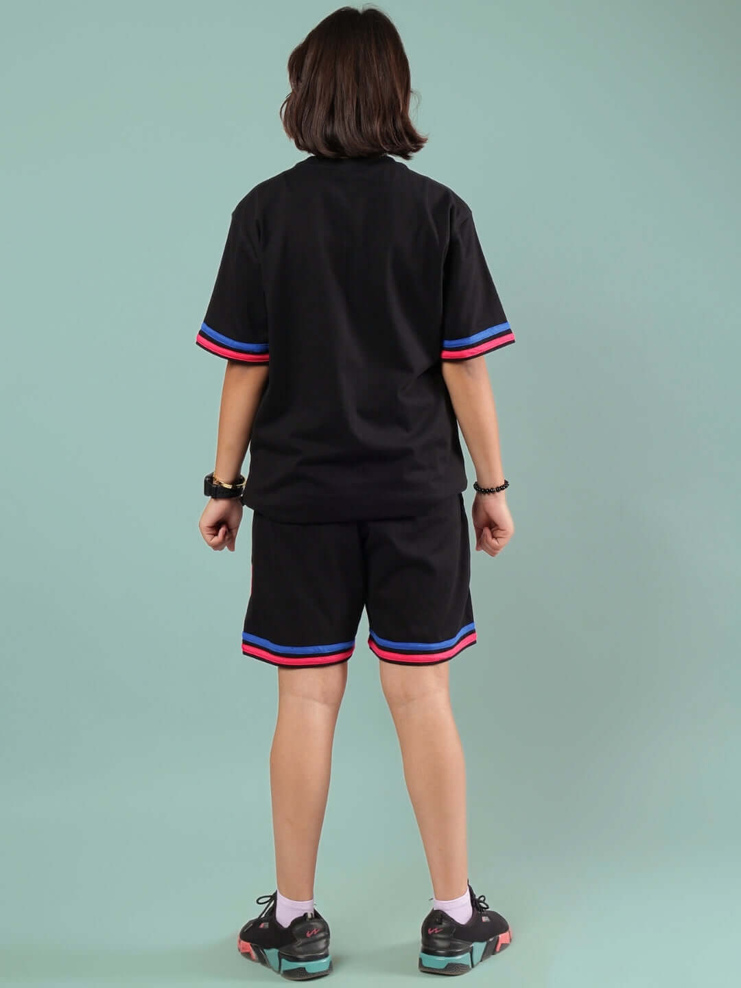 Child wearing MIAMI CO-ORD FOR BOYS & GIRLS BLACK with red and blue trim, handmade by DUDS Tailors.