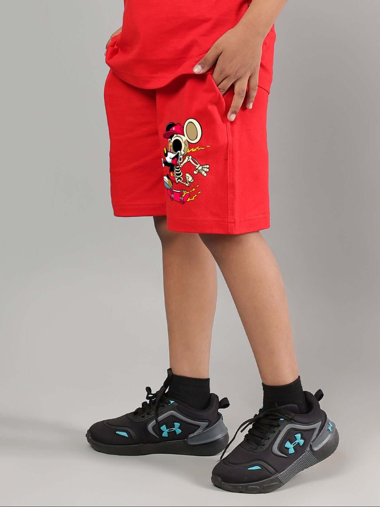 Child wearing red Mickey Mouse summer shorts for boys and girls, featuring a playful design and paired with black sneakers.