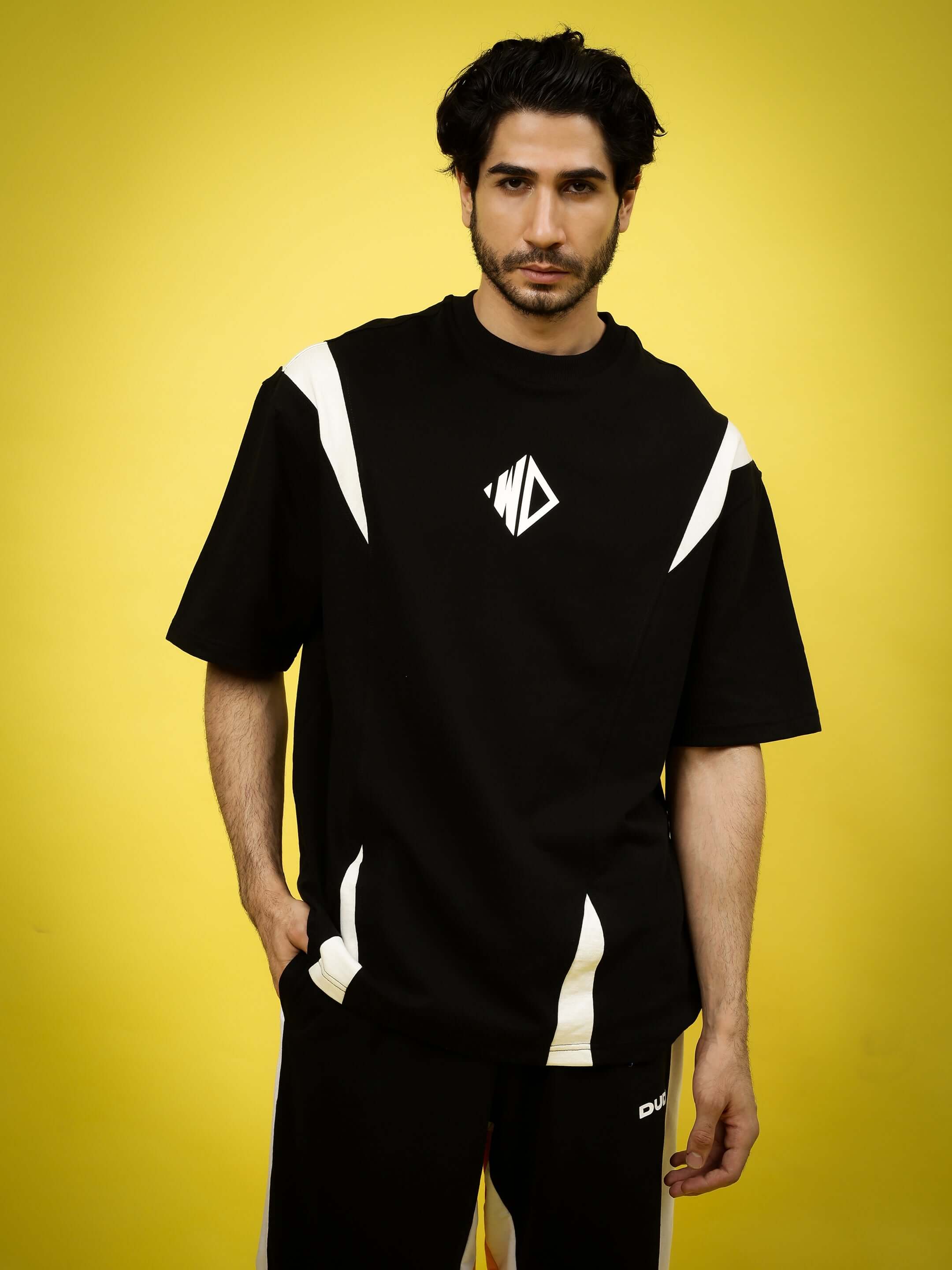 Black and white oversized t-shirt made from premium cotton French terry fabric, modeled with a modern fit against a yellow backdrop.