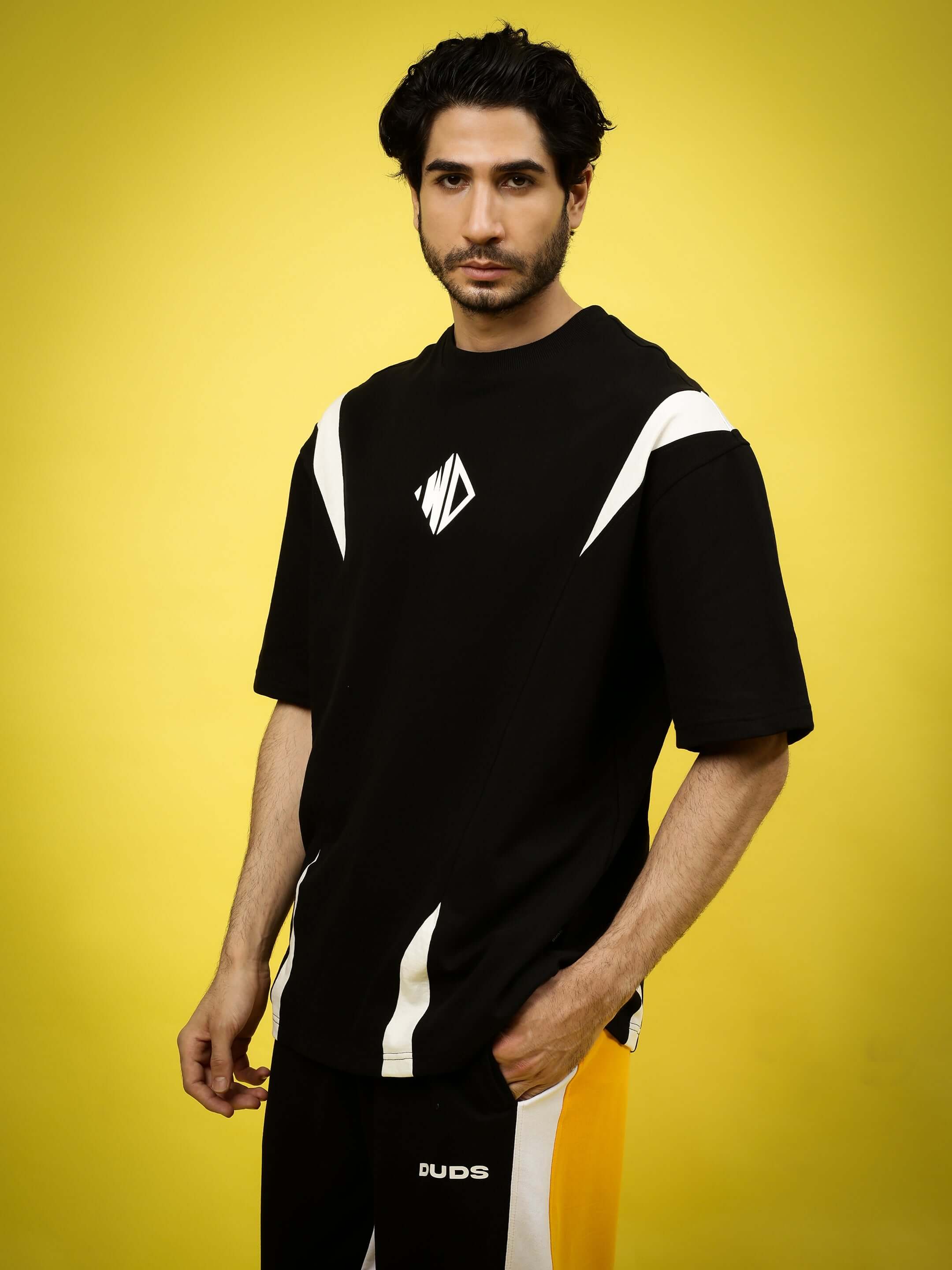 Model wearing MIGHTY MORPHIN oversized black-white T-shirt made from premium cotton fabric against a yellow background.
