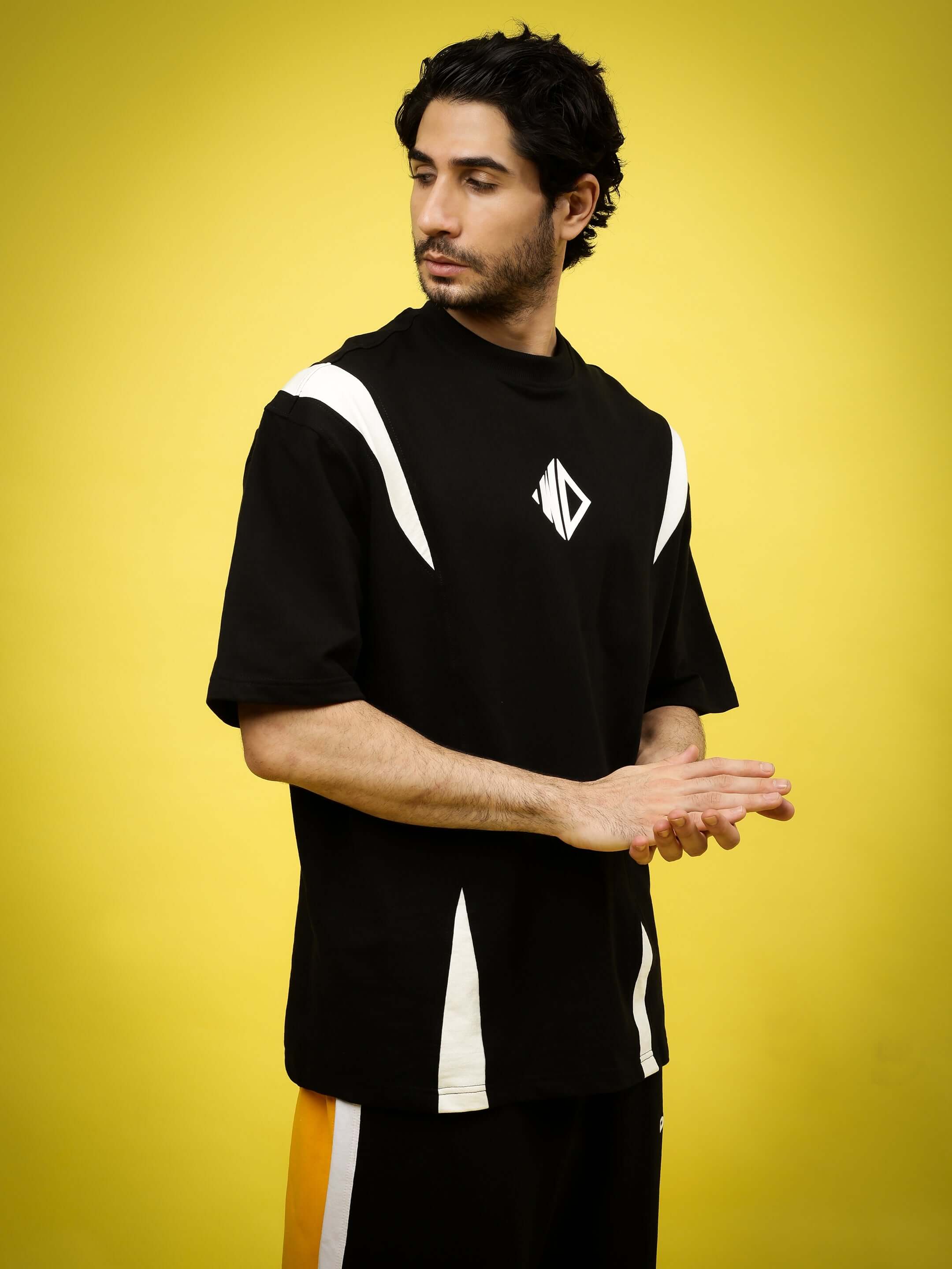 Black and white oversized T-shirt in premium cotton blend, worn by model against a yellow background. Fashion by Color By Colours.