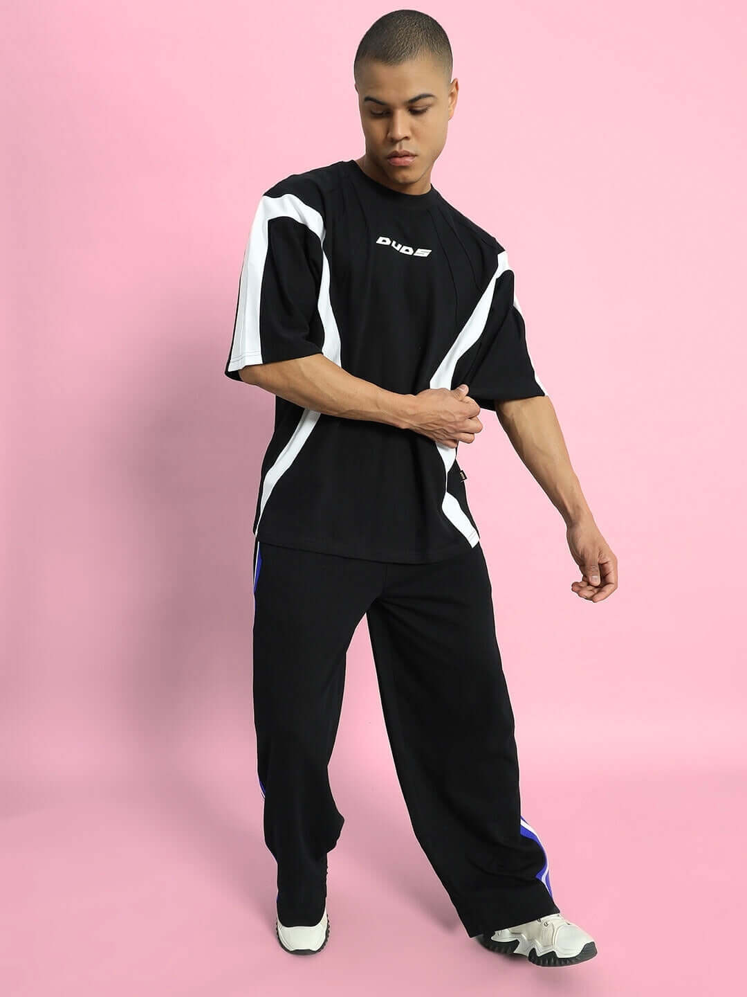 MILANO RELAXED-FIT JOGGERS BLACK-BLUE Person wearing black-blue MILANO relaxed-fit joggers by DUDS with a black and white top, standing against a pink background.