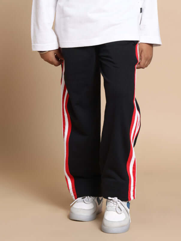 MILANO RELAXED PANT FOR BOYS & GIRLS JOGGER BLACK RED Child wearing black and red Milano Relaxed Jogger Pants, made to order by DUDS, paired with white sneakers and a long-sleeve top.