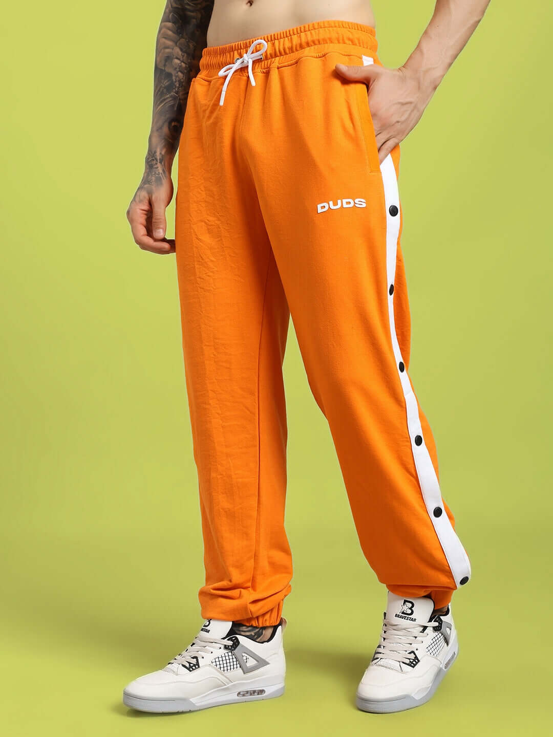 MILLER RELAXED FIT JOGGERS ORANGE displayed on model against green background.