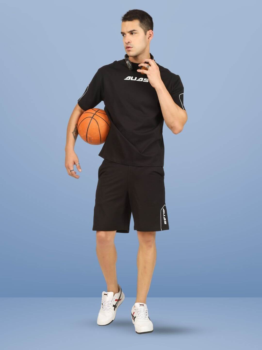 Man wearing minimal shaped regular fit shorts and holding a basketball on a blue background.