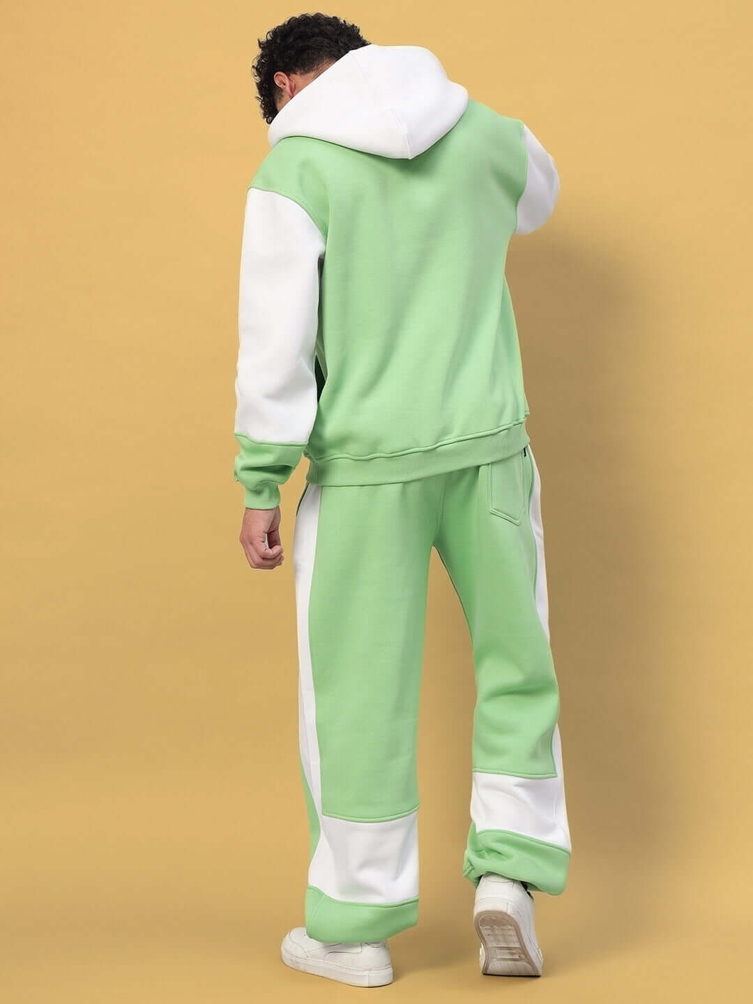 Person wearing MINTED BLISS FLEECE COLORBLOCK CO-ORD GREEN WHITE set with stylish green and white hoodie and joggers, rear view.