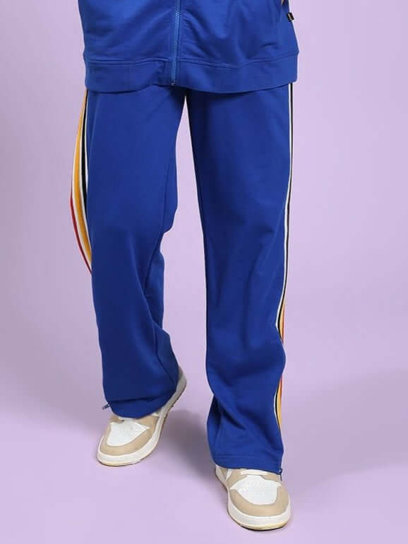 MODERN EDGE MULTI-STRIPE JOGGER ROYAL BLUE Blue tracksuit with colorful stripes on a light purple background