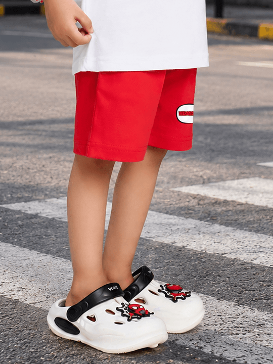 MONKEY BEATS COOL SHORTS FOR BOYS GIRLS RED worn by a child with trendy shoes on a city street.