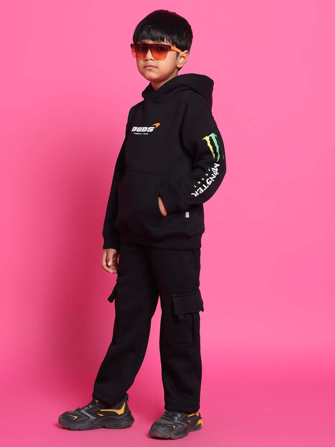 Child wearing MONSTER CO-ORD FOR BOYS GIRLS BLACK with monster graphics, standing against a pink background for imaginative play and adventure.