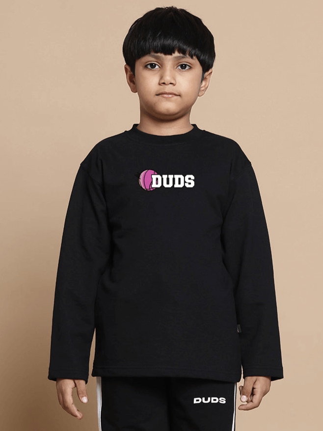 Child wearing a black oversized sweatshirt with "DUDS" logo, suitable for boys and girls. Made of premium 100% cotton fabric. Ideal casual wear.