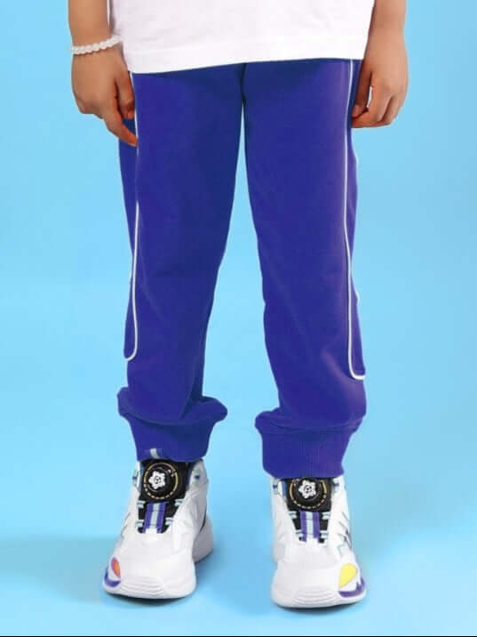 Child wearing MOON NIGHT JOGGER FOR BOYS & GIRLS BLUE with white sneakers, showcasing comfort and style for active kids on a blue background.