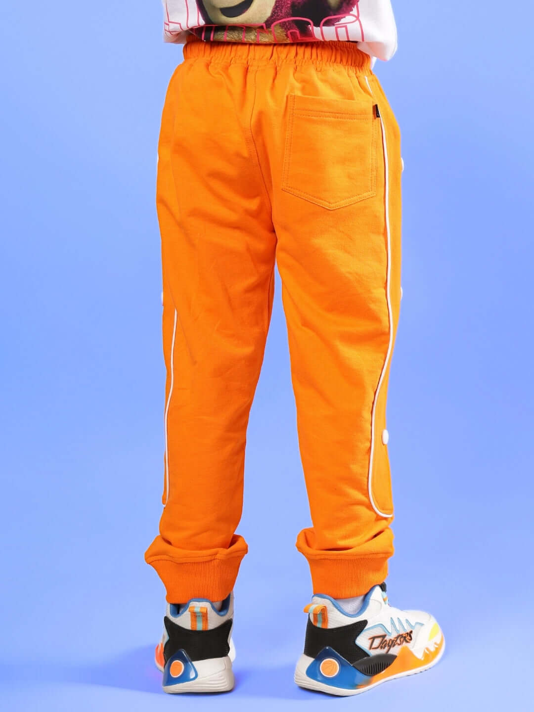 Child wearing vibrant orange jogger pants, designed for boys and girls, showcasing a comfortable fit and stylish pockets.