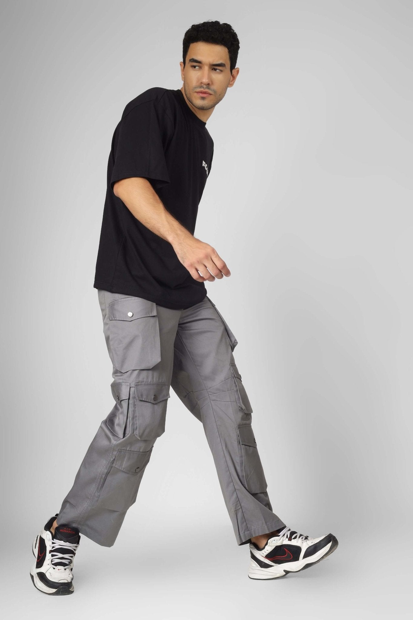 Man wearing MOON STONE CARGO PANTS WITH 12 CARGO POCKET in grey, showcasing streetwear style and practicality.