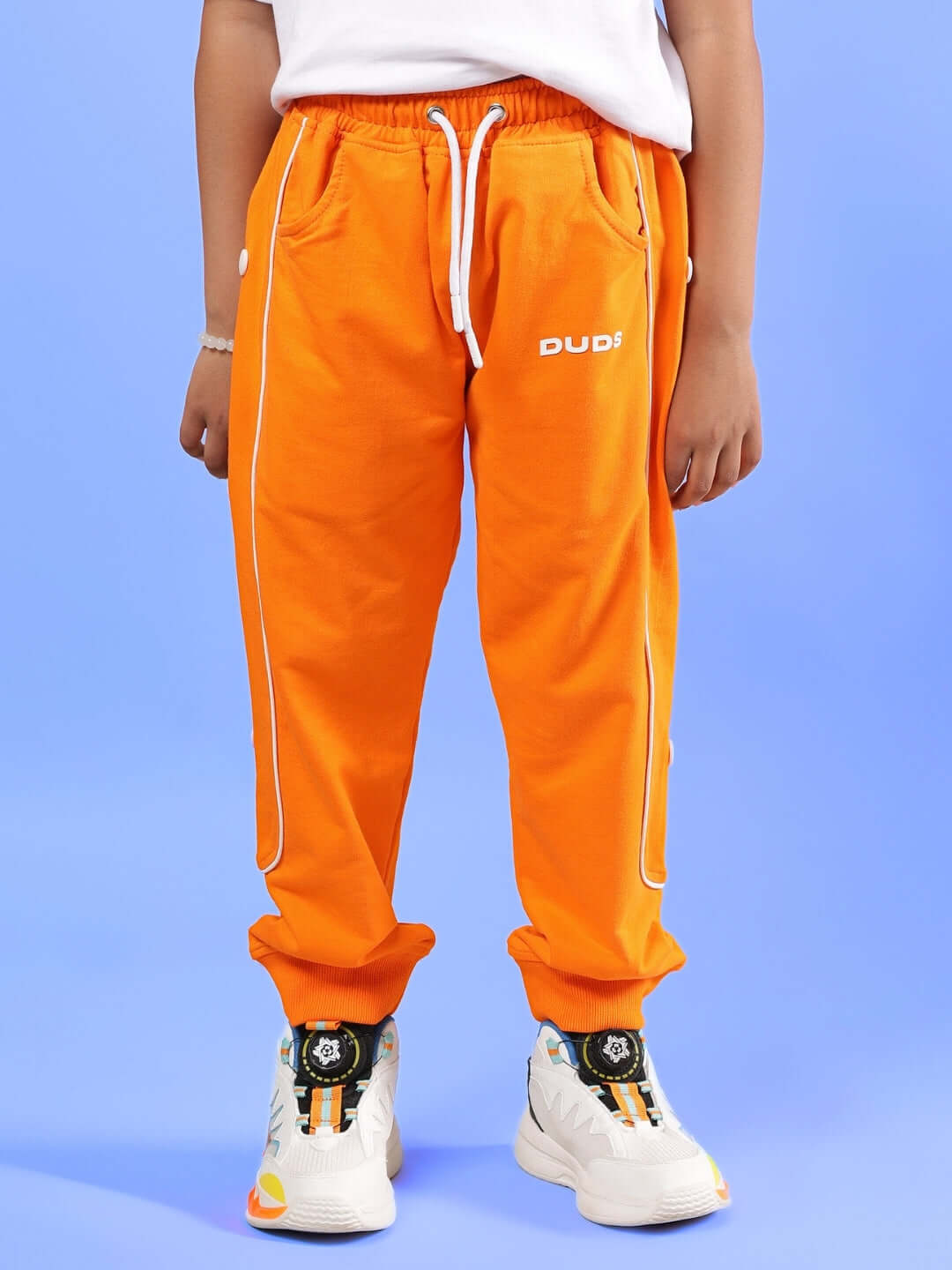 Child wearing orange joggers from DUDS, labeled MOON NIGHT JOGGER, perfect for boys & girls, showcasing stylish comfort.