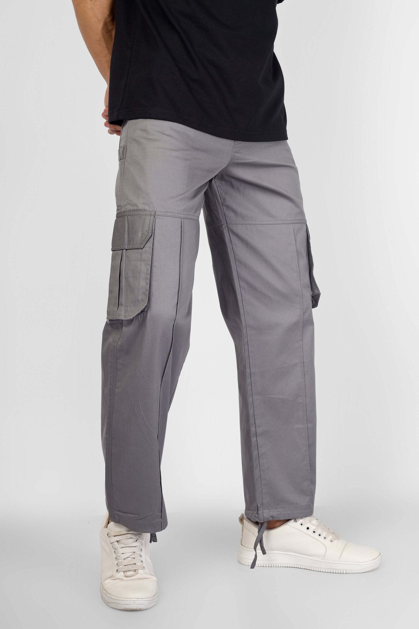 Model wearing MOON STONE CARGO PANTS WITH 6 CARGO POCKET in grey, showcasing streetwear style and practicality on white sneakers.