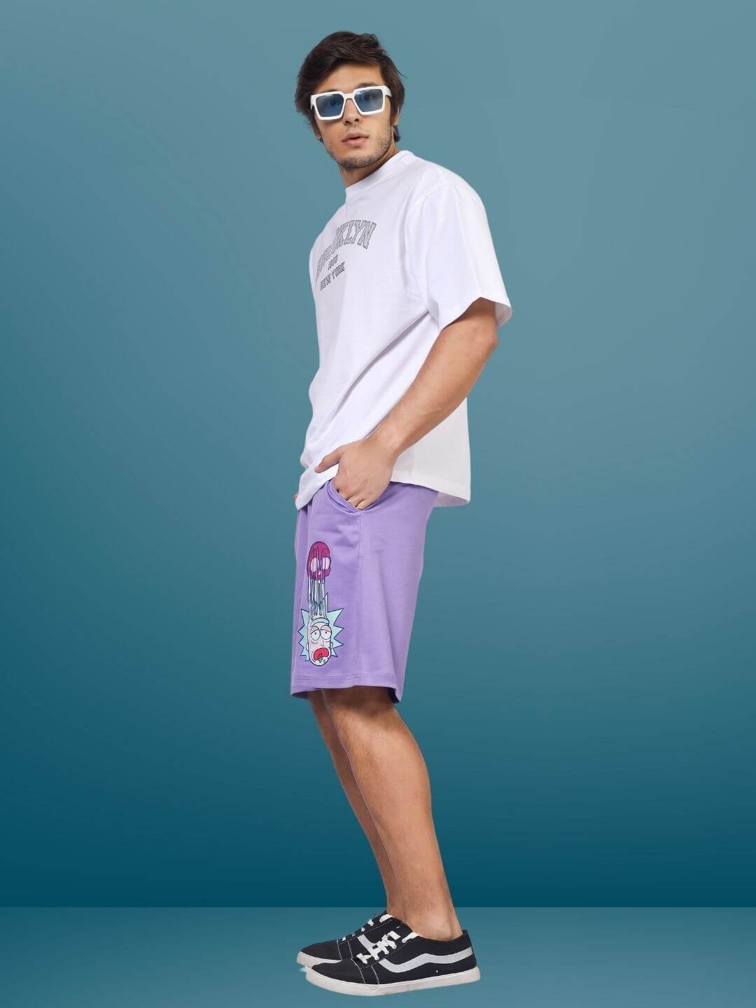 Model wearing Morty-fied regular fit lavender shorts, casual pose with hands in pockets, styled with white tee and sunglasses.