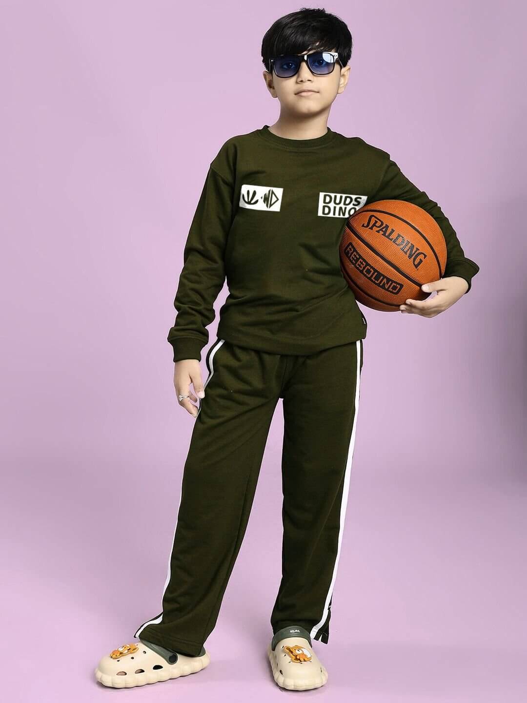 Child wearing MOSCOW RELAXED FIT JOGGER FOR BOYS AND GIRLS OLIVE GREEN, holding a basketball, showcasing a sporty and cool look.