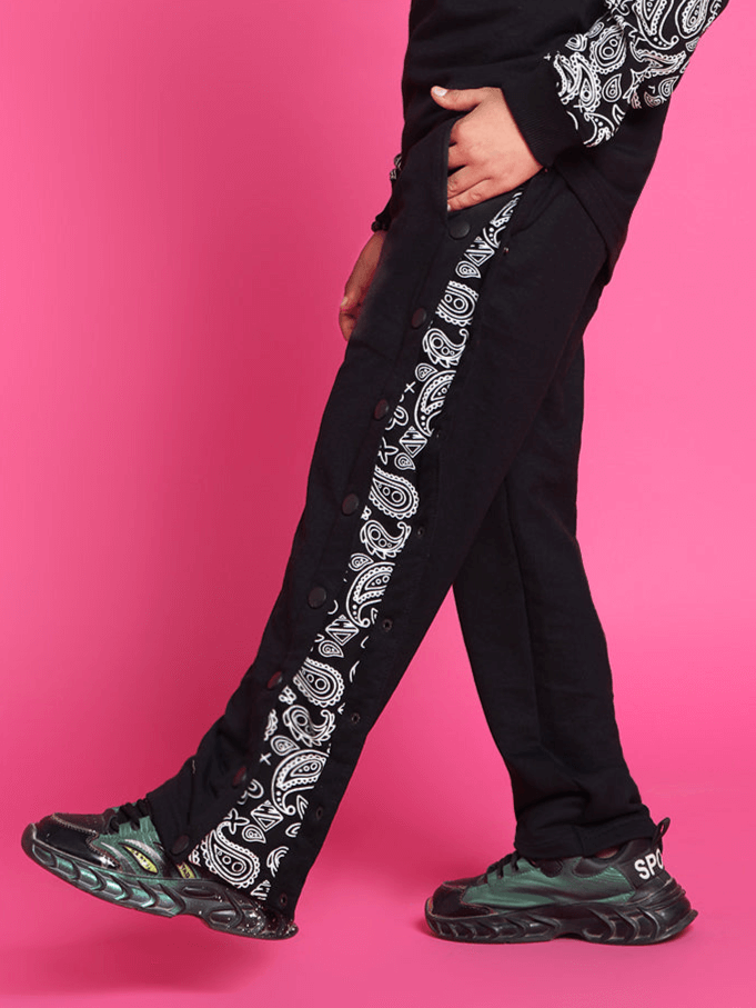 Motif joggers for boys and girls in black with side pattern, worn by child against pink background.