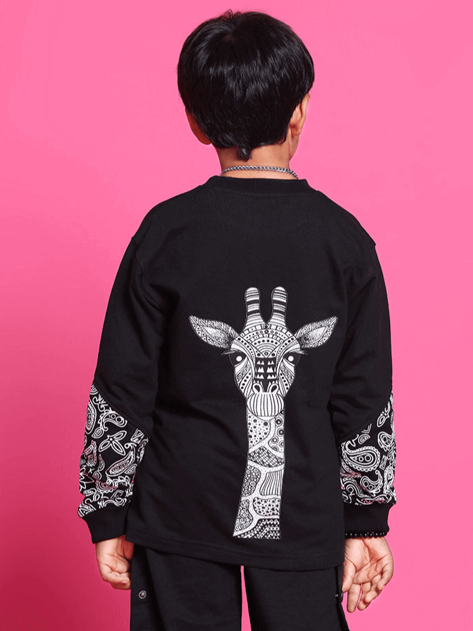 Child wearing black motif co-ord with giraffe design, created by DUDS, against a pink background.