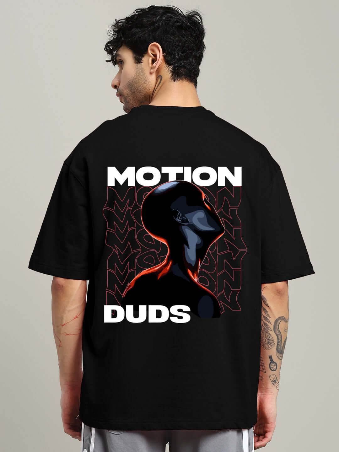 Black oversized t-shirt with 'Motion Duds' design, made from premium cotton French terry and elastane. Model shown from the back view.