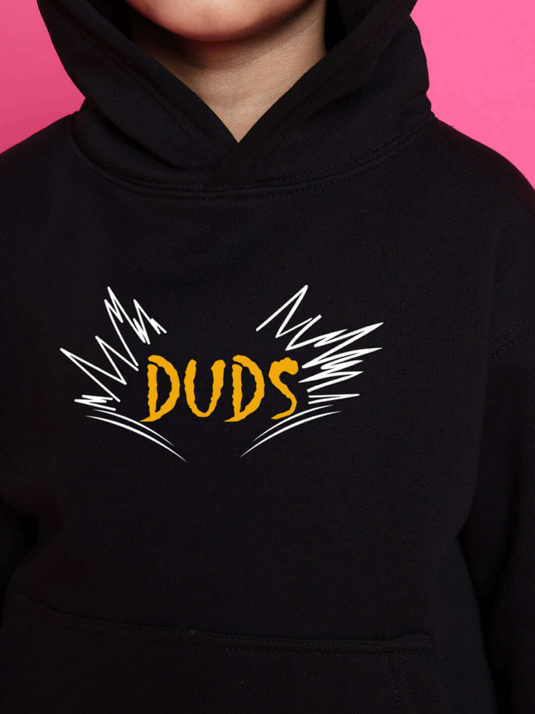 Child wearing black hoodie featuring 'DUDS' design on pink background.
